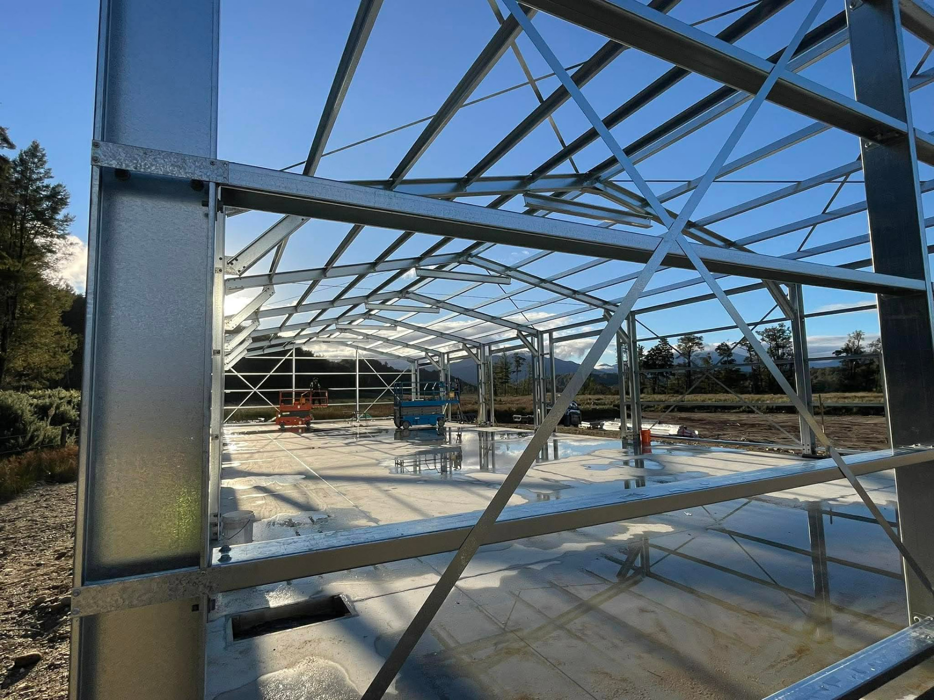 Real steel shed construction showing C-section girts bracketed between portal columns and roof purlins between rafters
