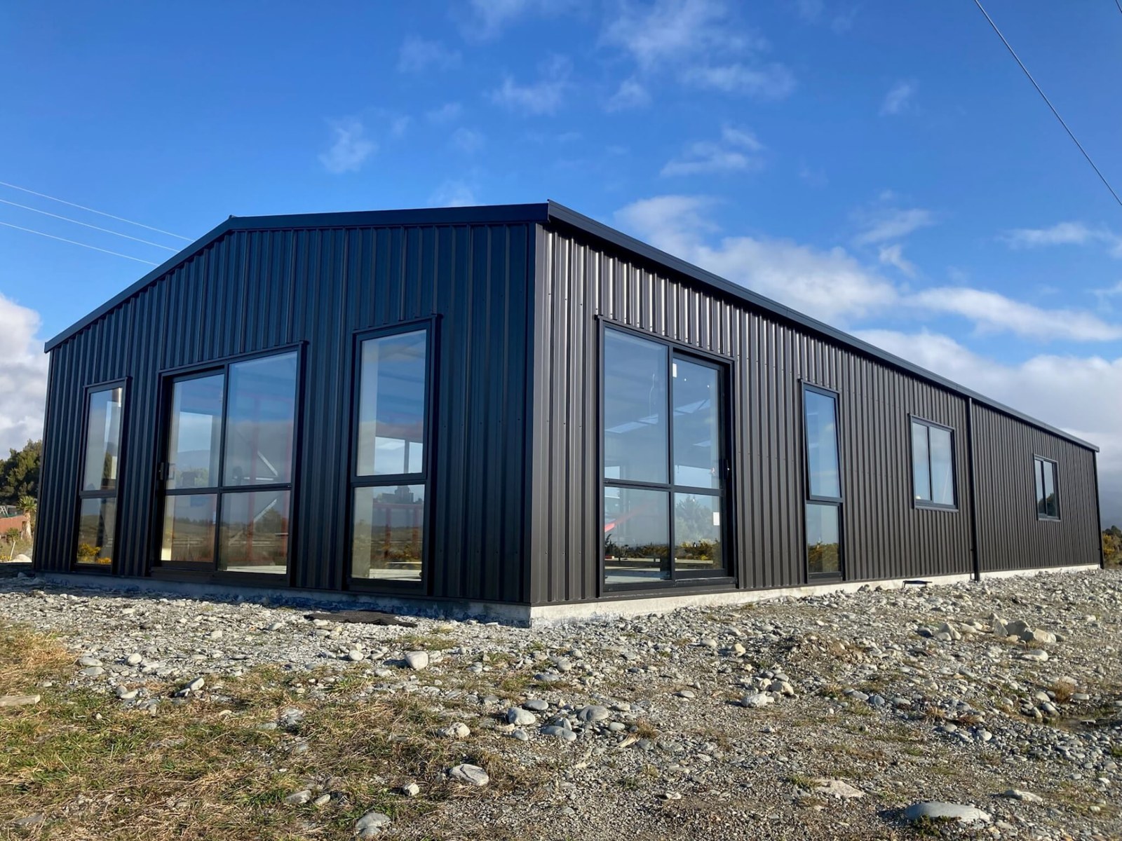 Single-storey black-clad shed home with full-height glazing and a mono-pitch roof
