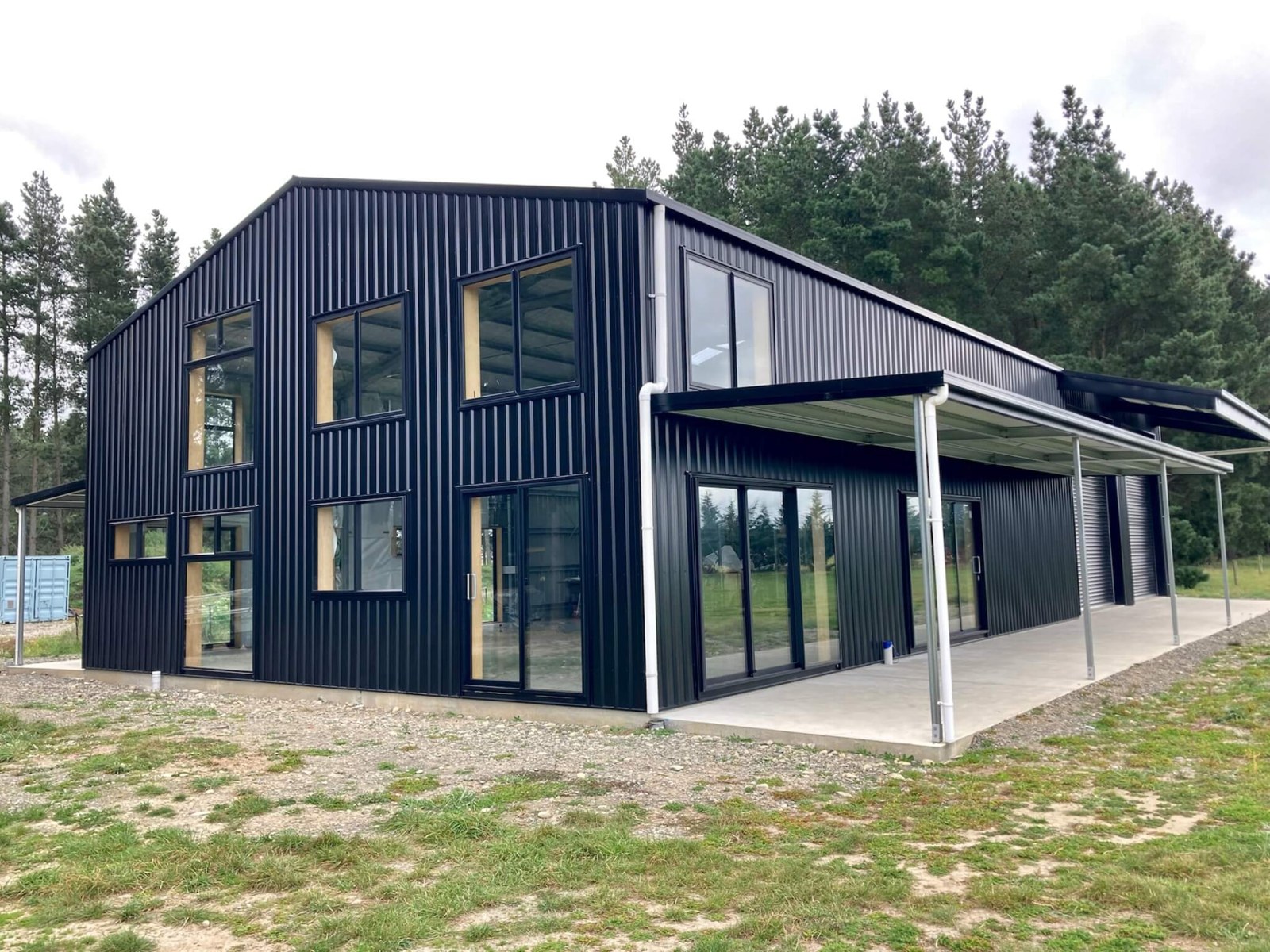Two-storey black-clad shed home with tall windows and a covered verandah
