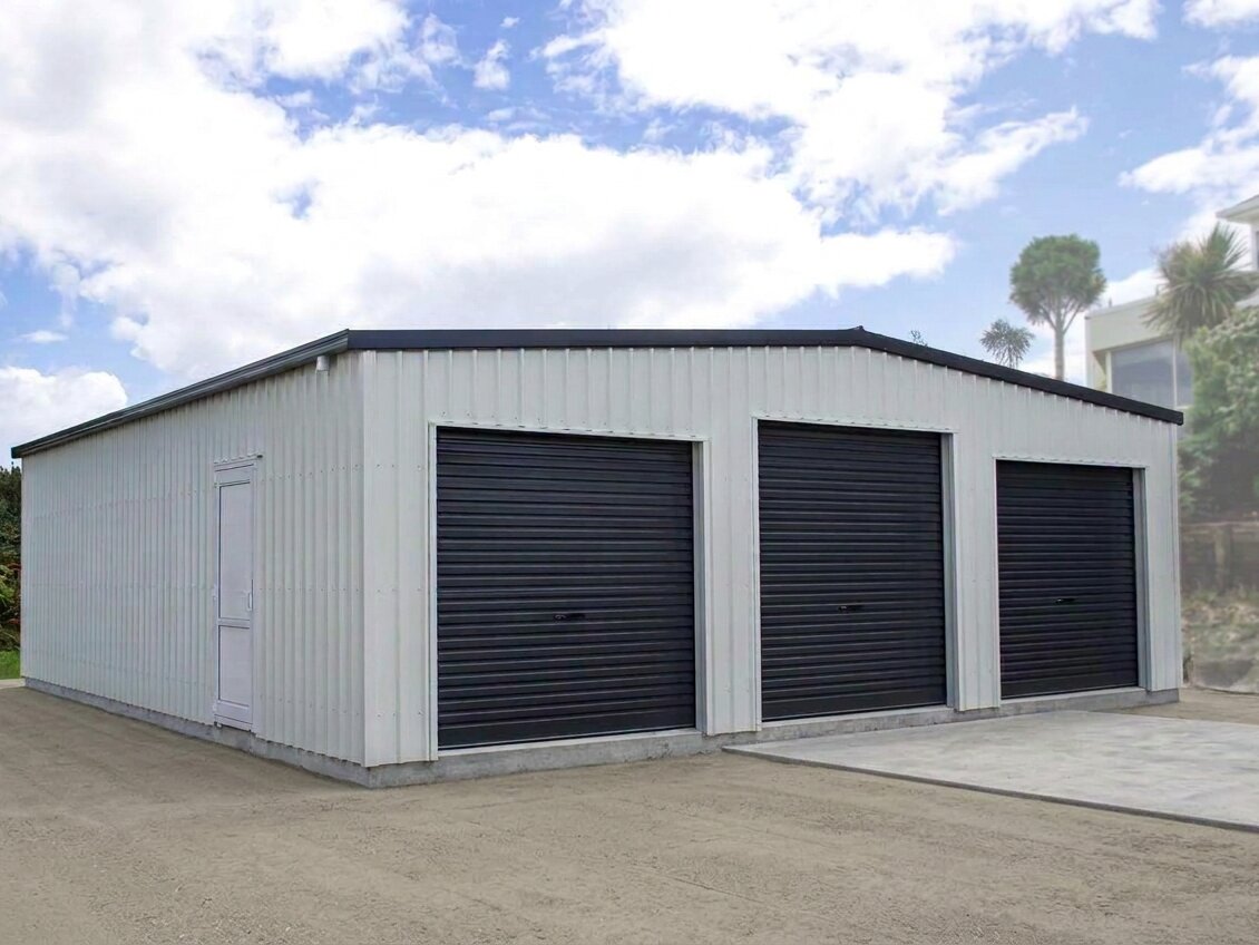 Cream three-bay workshop with dark trim, three roller doors and a side access door, built by 03 Sheds and Garages in Canterbury