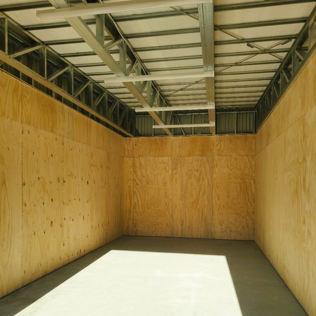 Inside a renovated 03 storage bay with plywood-lined walls, insulated roof panels and a clean concrete floor